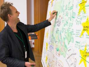 Graphic Recorder gibt das Bild mit Kreide Tiefe und Struktur und muss dabei lachen